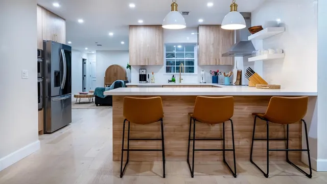 a kitchen with stainless steel appliances kitchen island granite countertop a table chairs refrigerator and microwave