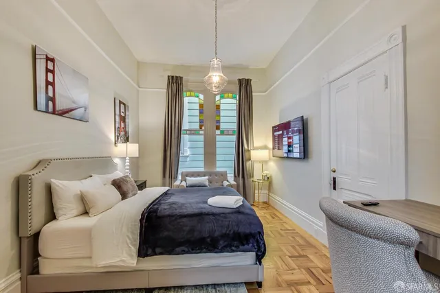 a spacious bedroom with a bed a couch and a chandelier