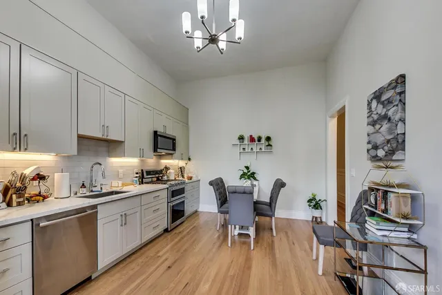 a kitchen with stainless steel appliances a dining table chairs refrigerator and sink