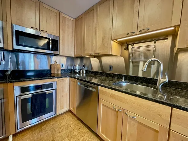 a kitchen with granite countertop a sink a stove top oven and cabinetry