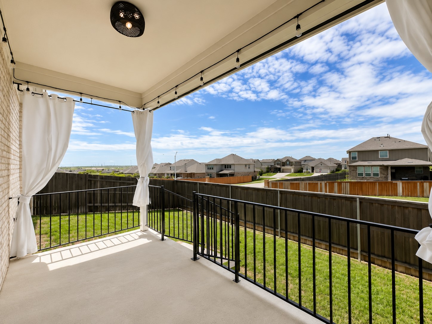 220 Pepperbark Loop Buda, TX 78610 - Photo 22 of 27 A covered back porch offers views of the fenced grassy yard under open skies.