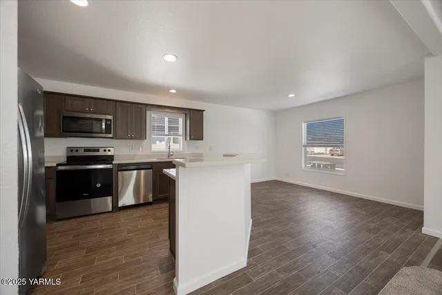 a kitchen with stainless steel appliances granite countertop a refrigerator a stove top oven a sink and dishwasher