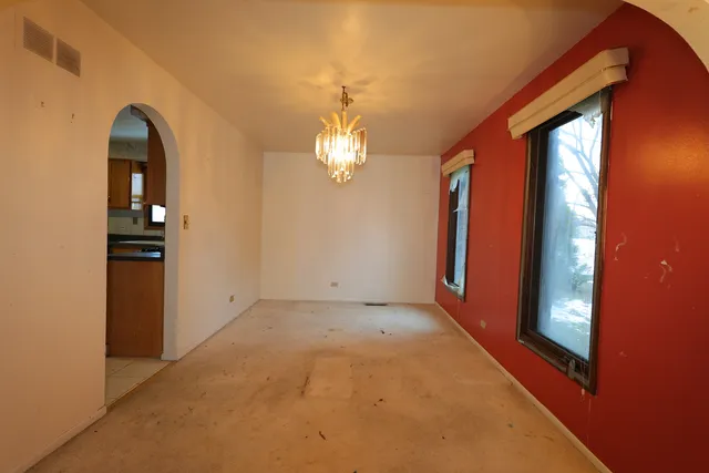 an empty room with chandelier fan and windows