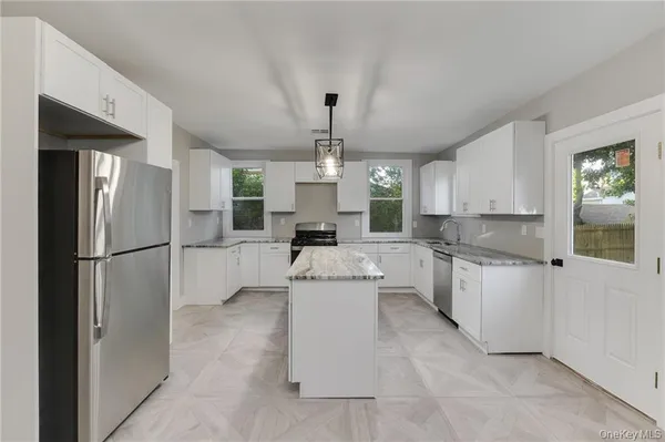 a kitchen with a refrigerator a sink dishwasher a stove and white cabinets