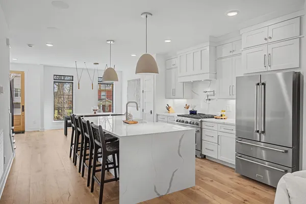 a kitchen with stainless steel appliances granite countertop a refrigerator a sink dishwasher a stove and white cabinets with wooden floor