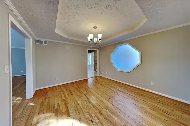 an empty room with wooden floor and chandelier