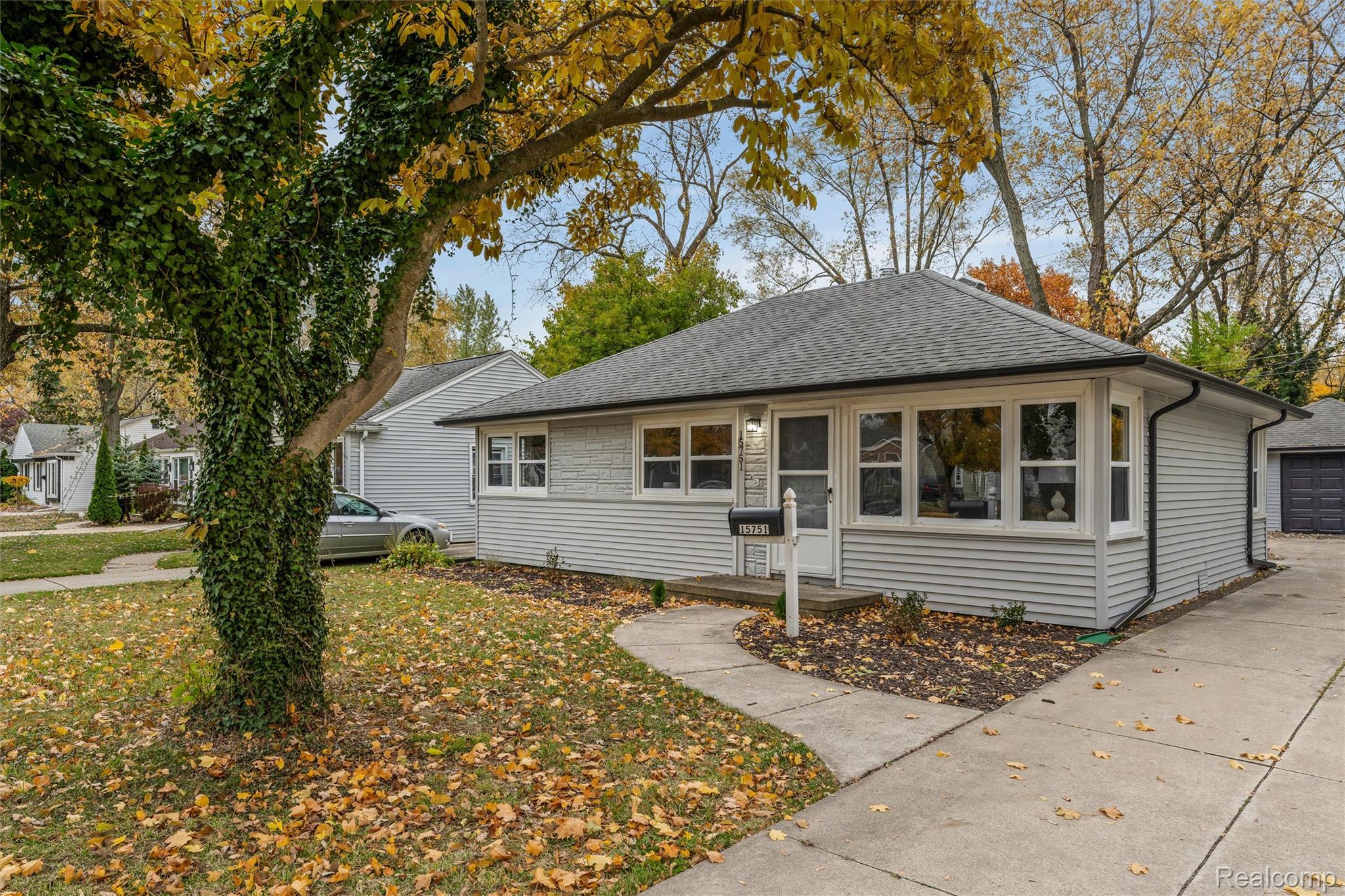 Single-story residence featuring light gray siding, a dark shingle roof, and a concrete driveway