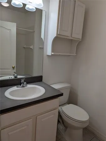 a bathroom with a granite countertop toilet sink and mirror