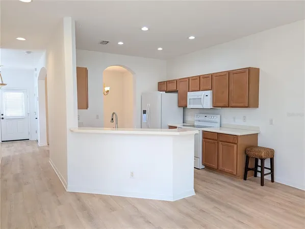 a large kitchen with stainless steel appliances a large counter top a stove a sink and a refrigerator