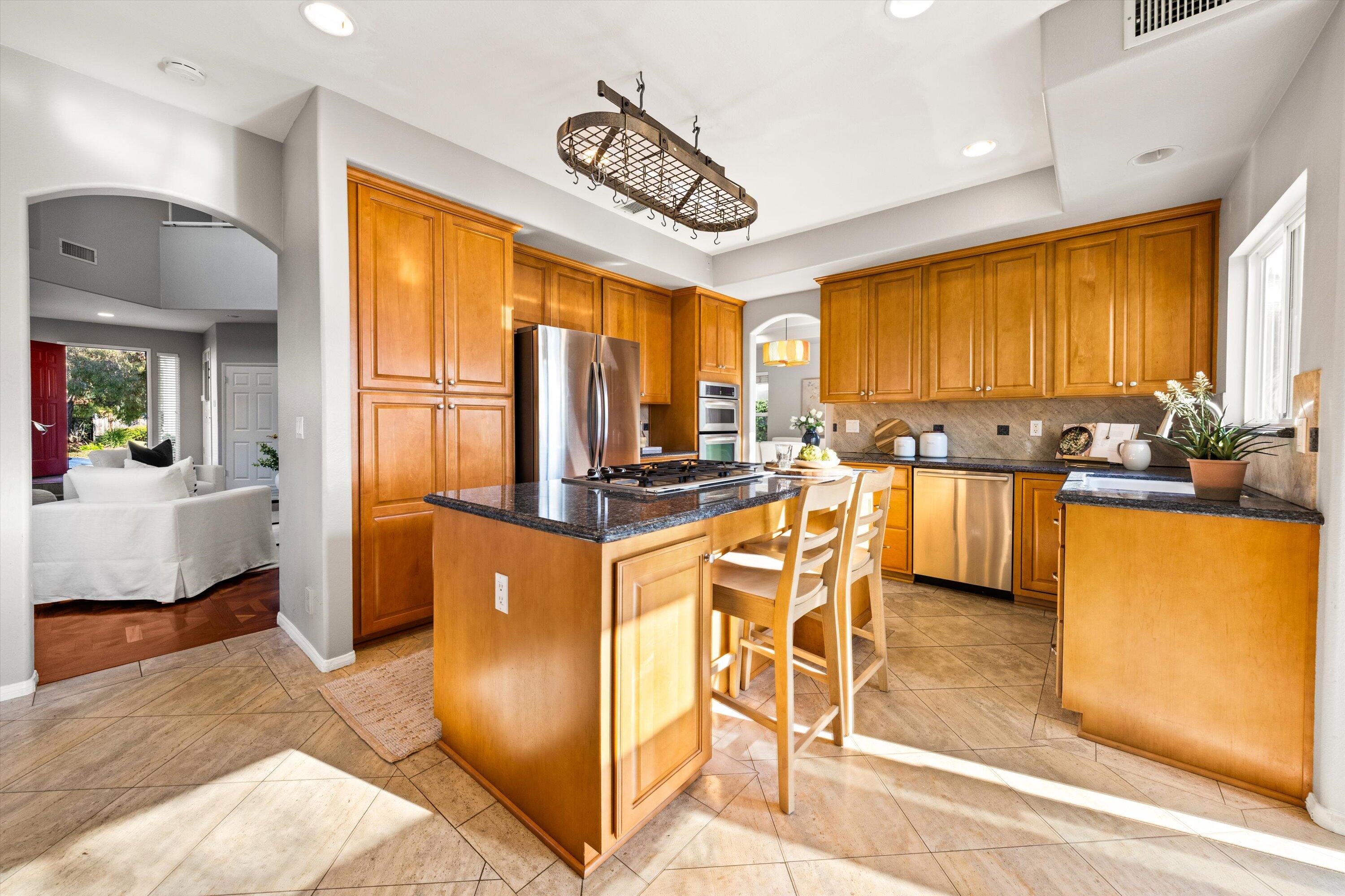 7926 Winchester Circle Goleta, CA 93117 - Photo 11 of 56 a kitchen with stainless steel appliances kitchen island granite countertop a refrigerator a stove top oven and a dining table with wooden floor