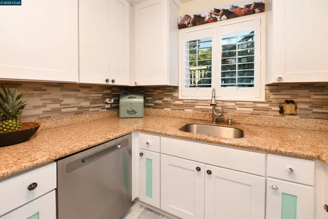 a kitchen with stainless steel appliances granite countertop a sink and a white cabinets