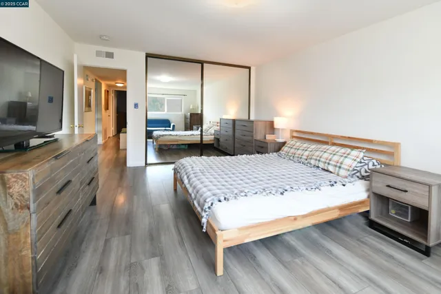 a spacious bedroom with a bed and wooden floor