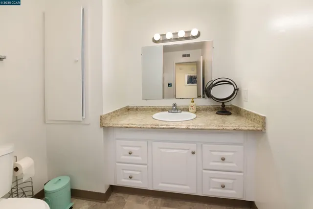 a bathroom with a granite countertop sink and a mirror