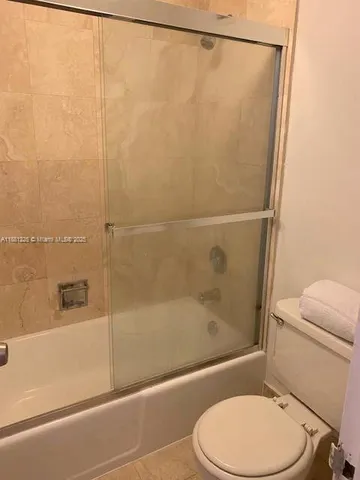 a white toilet sitting next to a bath tub and a shower