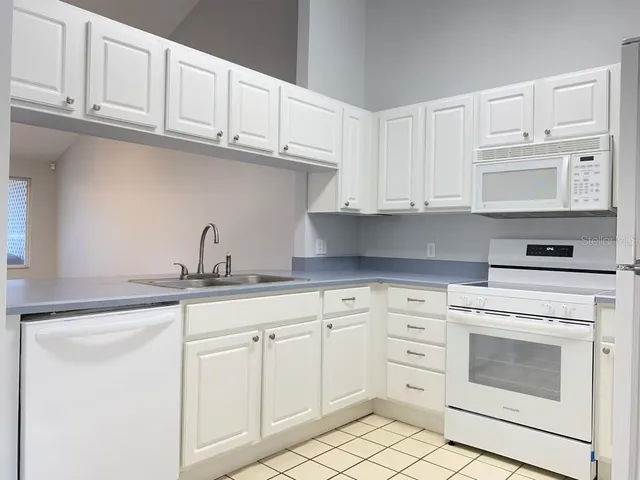 a kitchen with white cabinets and white appliances