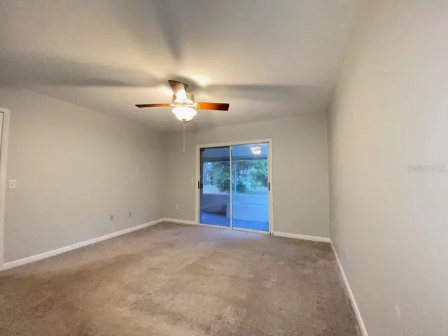 an empty room with a ceiling fan and window