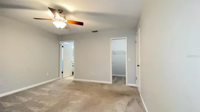 an empty room with closet and a chandelier fan