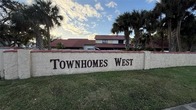 a view of outdoor space with sign board and tree in the background