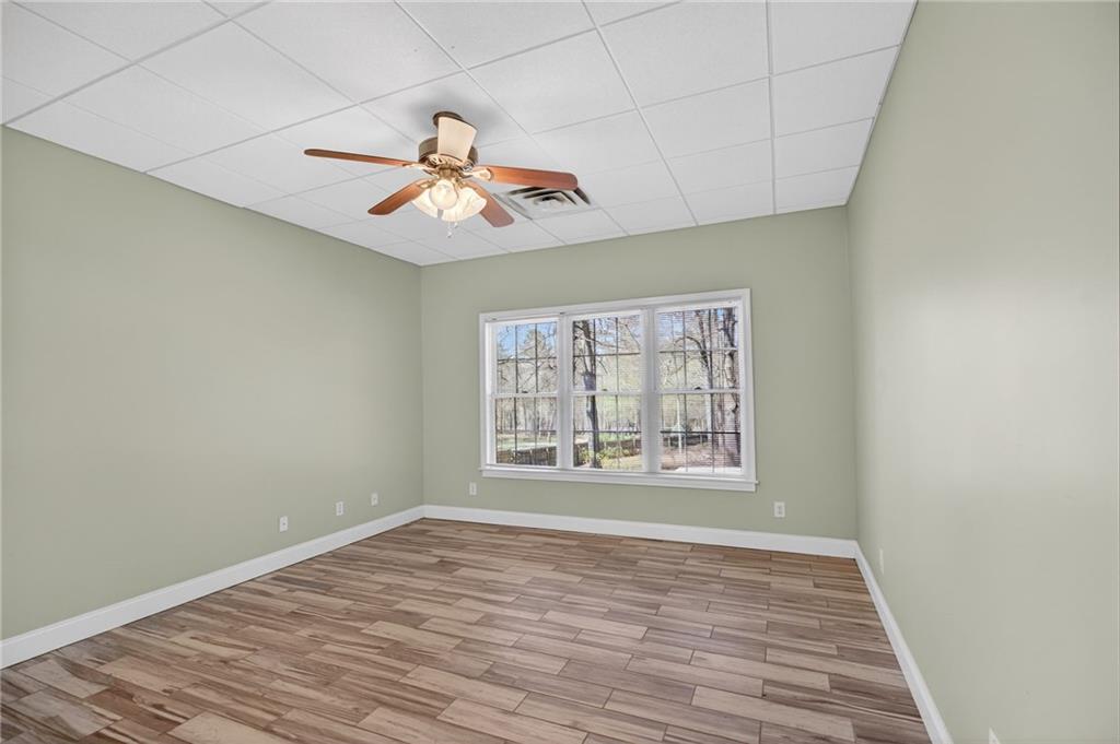 129 Oak Walk Villa Rica, GA 30180 - Photo 56 of 78 an empty room with wooden floor chandelier fan and windows