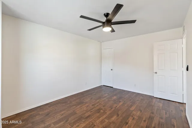 a view of empty room with wooden floor and ceiling fan