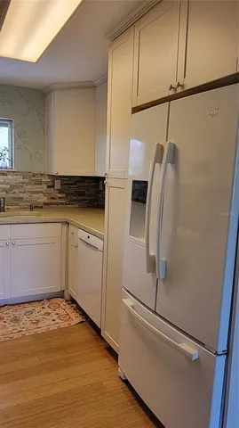 a kitchen with stainless steel appliances a refrigerator a sink and white cabinets