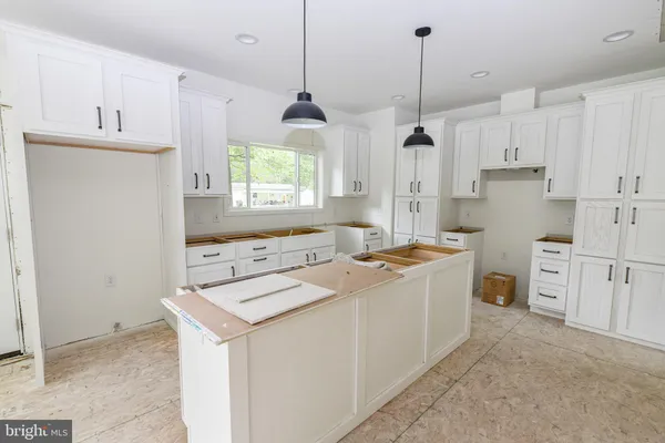 a kitchen that has a lot of white cabinets and stainless steel appliances