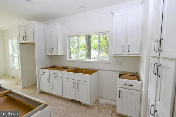 a kitchen with white cabinets and sink