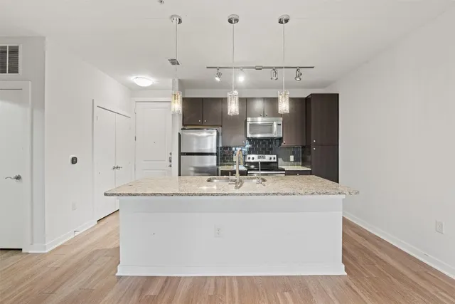 a view living room with granite countertop kitchen island stainless steel appliances a sink and wooden floor