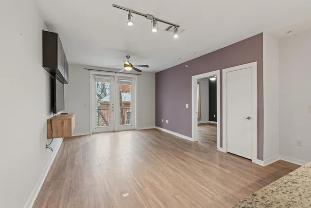 a view of an empty room with a window and wooden floor