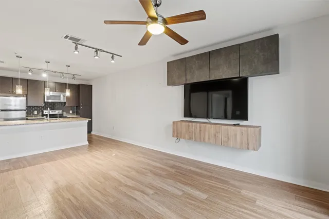 a view of kitchen and empty room with wooden floor