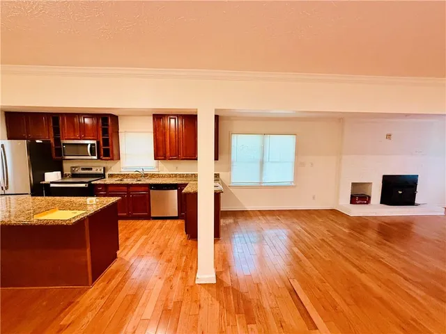 a large kitchen with kitchen island granite countertop wooden floors and stainless steel appliances