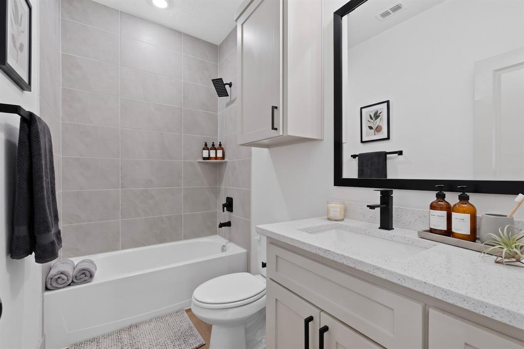 103 Cherokee Street Terrell, TX 75160 - Photo 29 of 40 (Virtual Staging)Full bathroom featuring a rectangular bathtub, tiled shower surround, recessed lighting, a single vanity with a solid surface countertop, and matte black fixtures