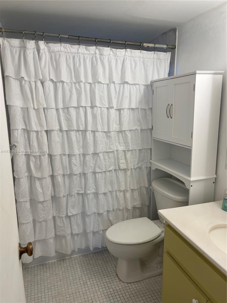 7787 Southwest 86th Street, Unit E211 Miami, FL 33143 - Photo 16 of 27 a bathroom with a toilet and a shower curtain