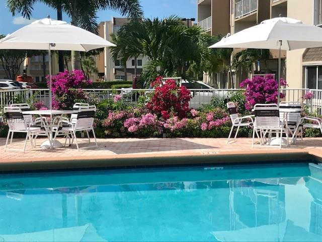 7787 Southwest 86th Street, Unit E211 Miami, FL 33143 - Photo 19 of 27 a view of a chairs and table under an umbrella in front of building