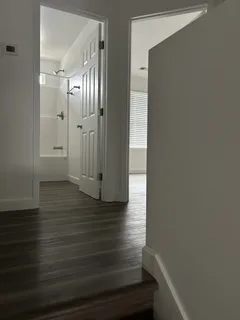 a view of an empty room with wooden floor and a window