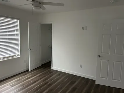a view of an empty room with wooden floor and a window