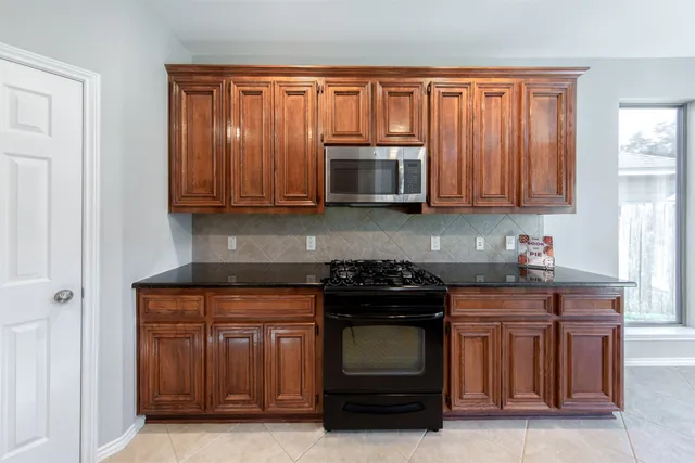 a kitchen with granite countertop a stove top oven microwave and cabinets