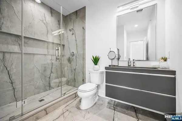 a bathroom with a granite countertop sink a toilet and shower