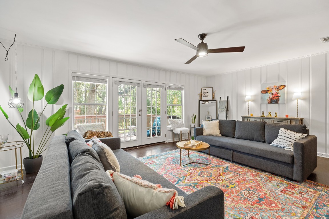 Living area featuring dark wood-style flooring, ceiling fan, and french doors