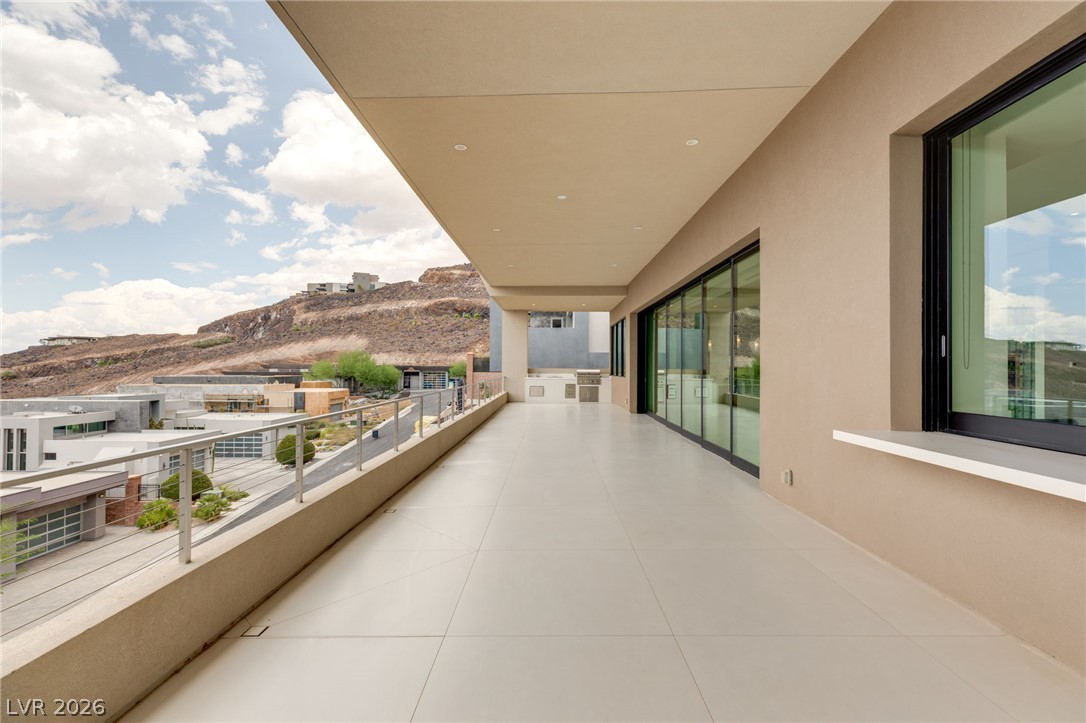 677 Overlook Rim Drive Henderson, NV 89012 - Photo 61 of 97 An expansive covered balcony features sleek tiled flooring and sliding glass doors under recessed lighting.