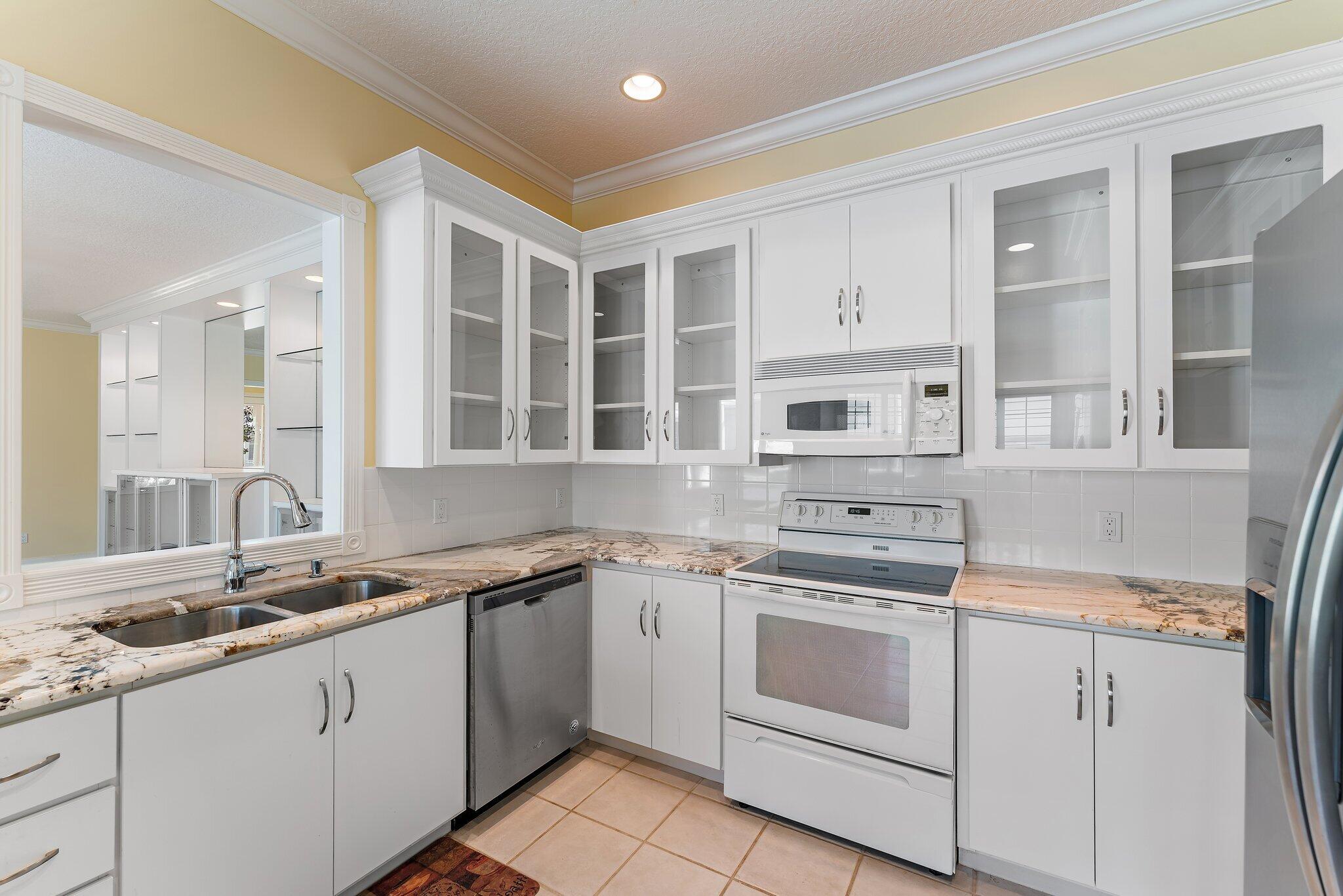 215 New Haven Boulevard Jupiter, FL 33458 - Photo 15 of 42 a kitchen with granite countertop white cabinets and white appliances