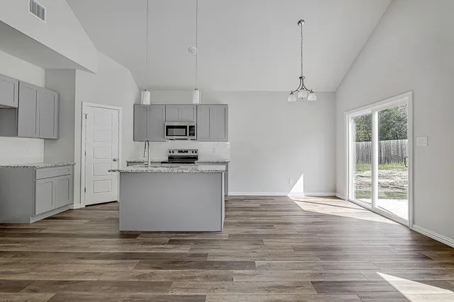 a kitchen view with wooden floor and stainless steel appliances