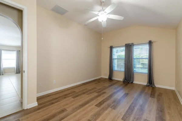 an empty room with wooden floor and a ceiling fan