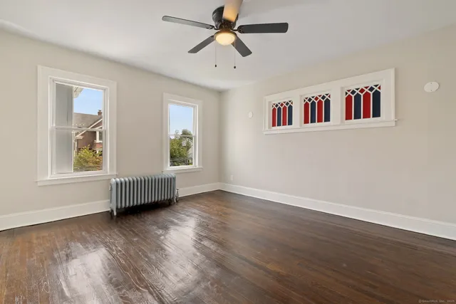 a view of an empty room with window and wooden floor