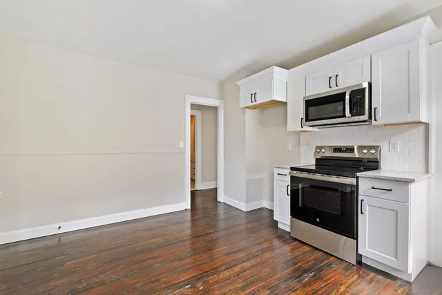 a kitchen with stainless steel appliances granite countertop a stove a microwave and white cabinets