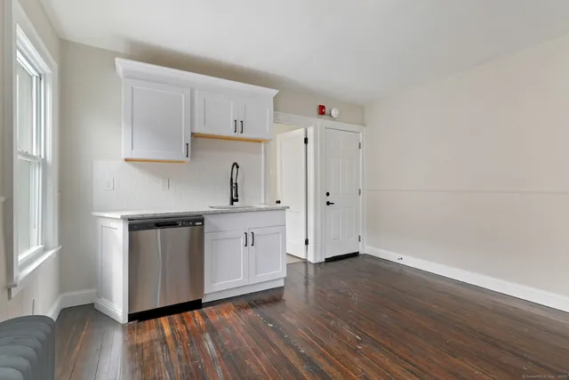 a kitchen with granite countertop white cabinets and wooden floor