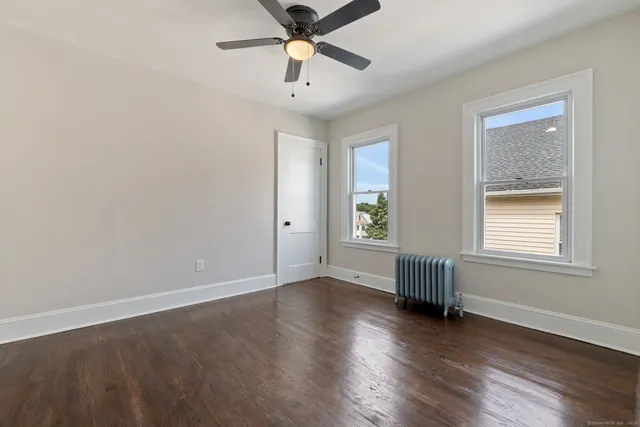 an empty room with wooden floor fan and windows