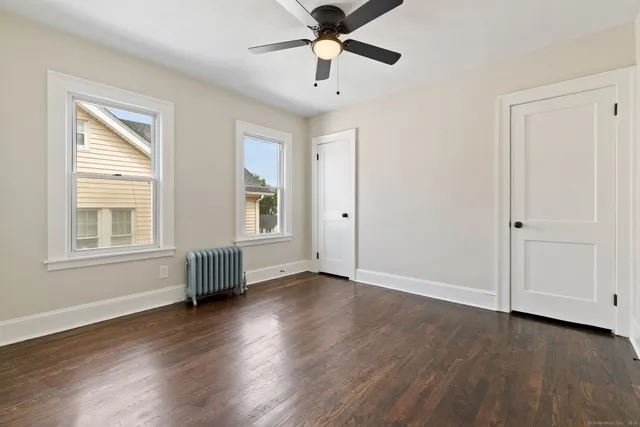 a view of an empty room with window and wooden floor