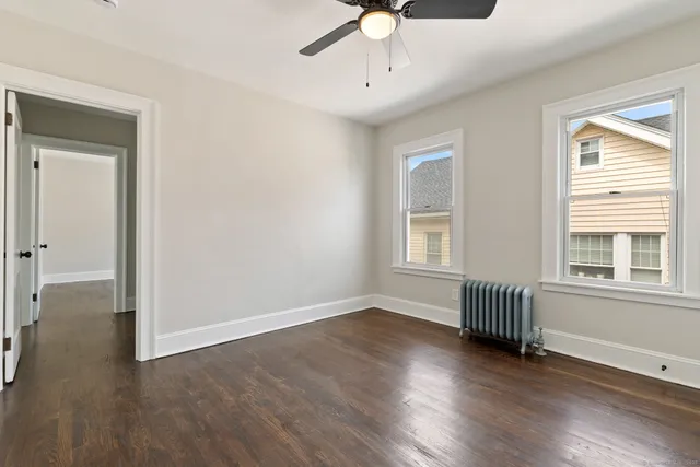 a view of an empty room with a window and wooden floor