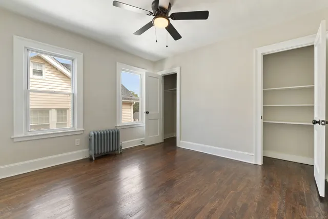 a view of an empty room with a window and wooden floor